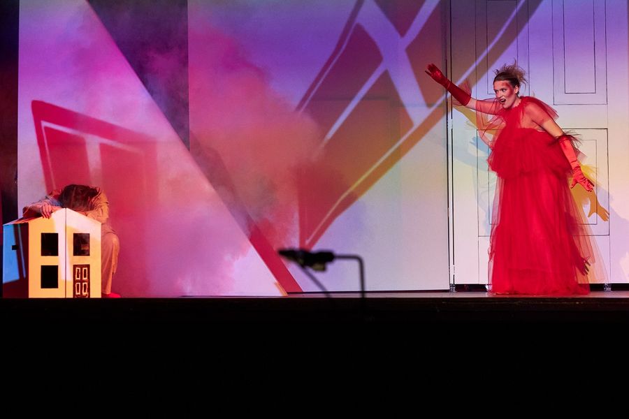 Eine Sängerin in einem roten Kleid mit wilden Haaren, daneben sitzt eine Sängerin