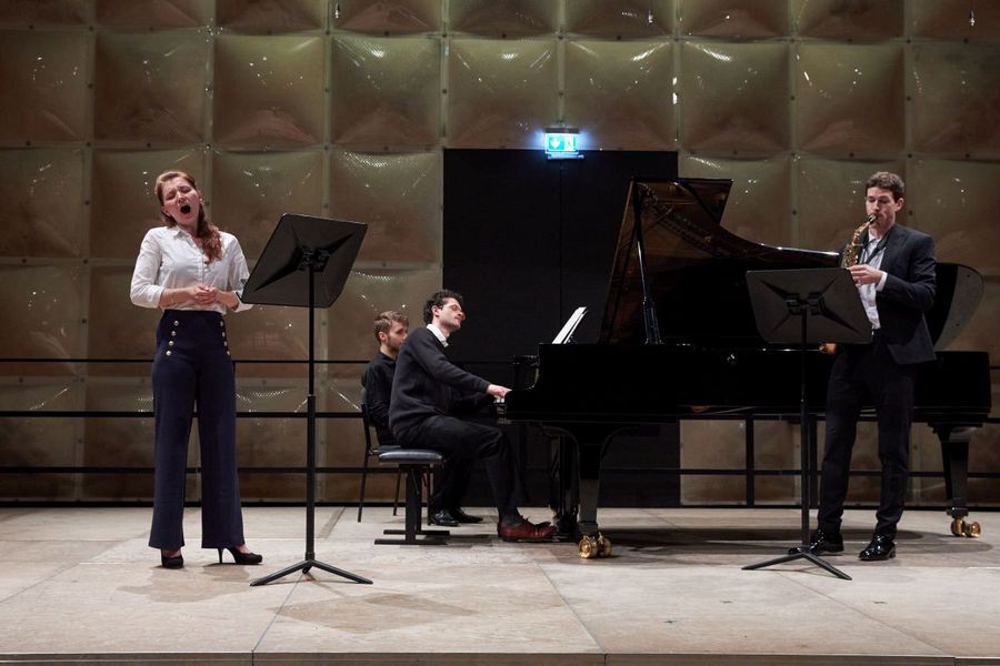 Eine Studentin singt, neben ihr ein Student am Klavier und ein Student am Saxophon