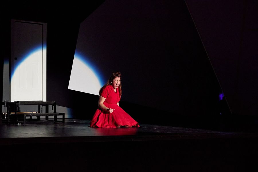 eine Sängerin in einem roten Kleid sitzt auf der schwach beleuchteten Bühne