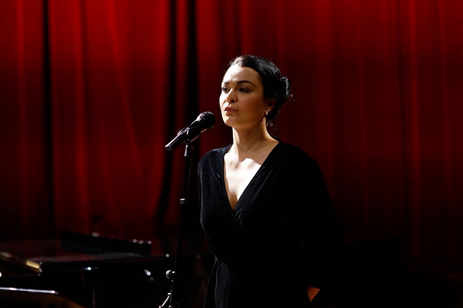 Gesangstudentin auf der Bühne des Studiosaals vor rotem Vorhang