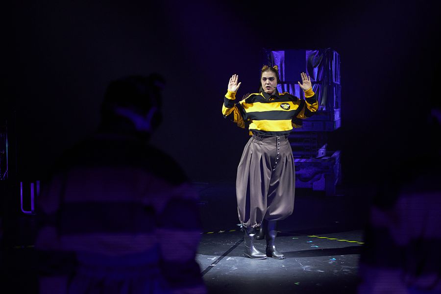 Als Biene verkleidete Sängerin steht mit erhobenen Händen auf einer Bühne