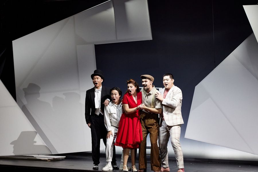 eine Sängerin und vier Sänger stehen Arm in Arm auf der Bühne