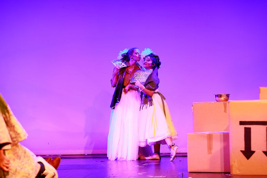 Zwei Studentinnen in Kostümen auf einer Opernbühne mit Pappkartons