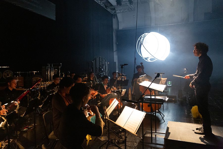 Mann dirigiert ein Orchester im Dunkeln