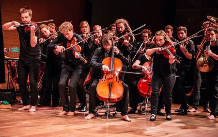 Orchester steht spielend auf einer Bühne 