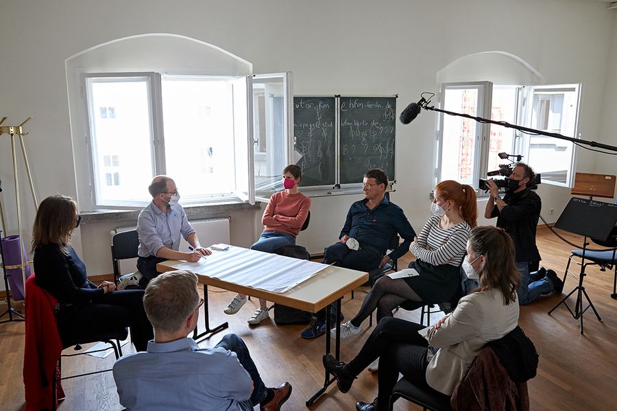 Hochschulangehörige sitzen um einen Tisch und unterhalten sich 