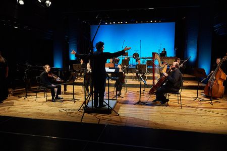 Hochschulprofessor und Studierenden-Ensemble auf einer Bühne nach beendigtem Konzert