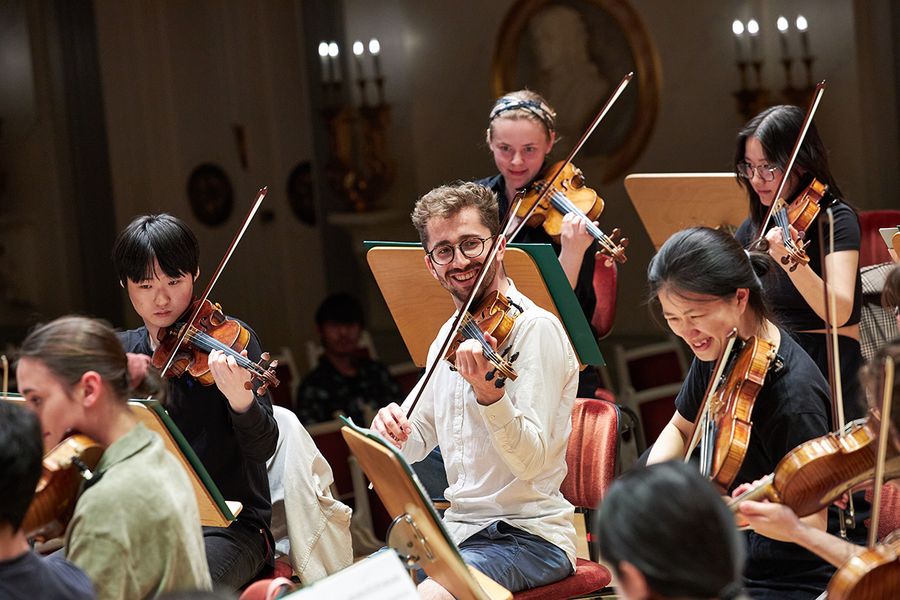 Studierende spielen Geige in einem Orchester