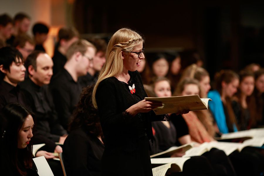 Singende Studentin vor einem Chor aus Studierenden während eines Konzertes