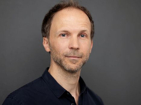 Mann mit Dreitagebart vor grauem Hintergrund