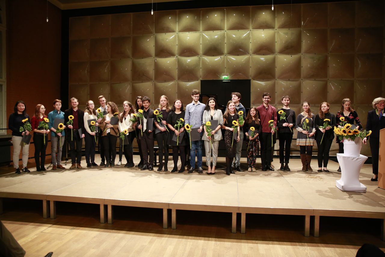 Studierende mit Blumen und Urkunden auf einer Bühne
