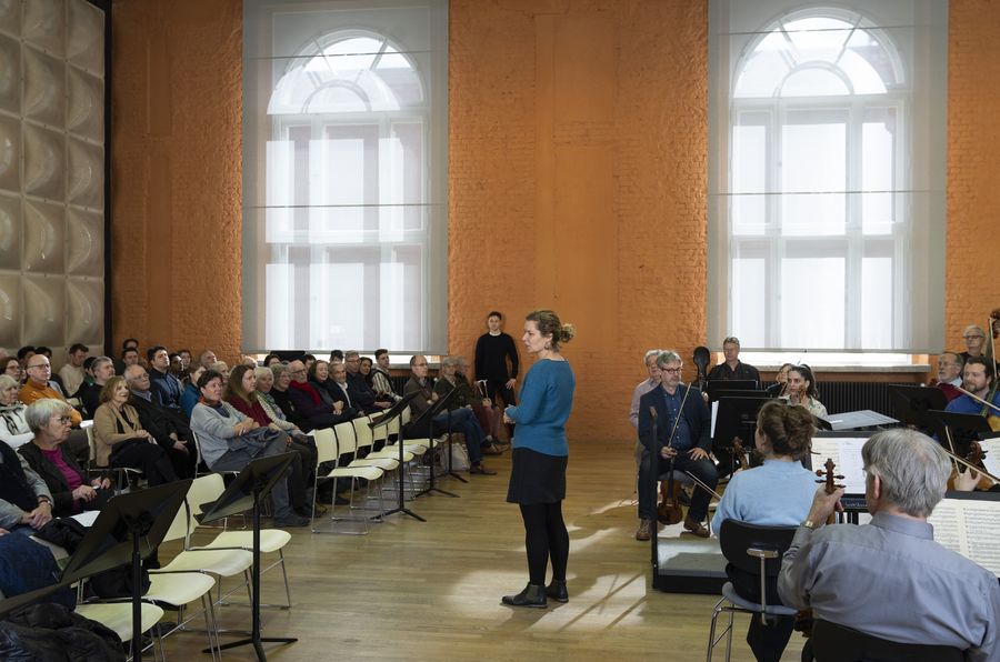 Frau in türkis gekleidet redet mit Publikum