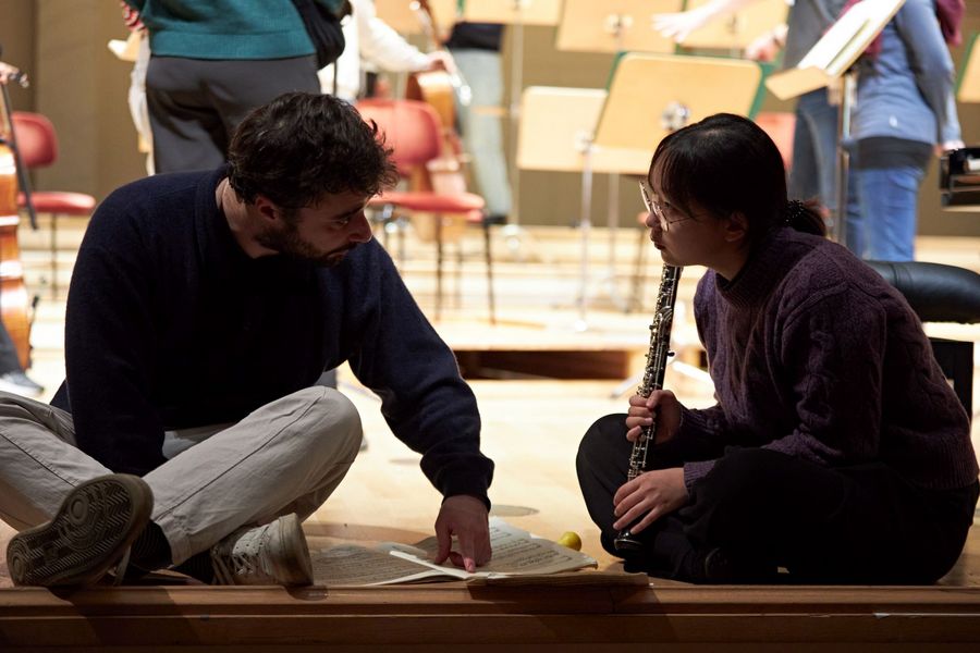Pianist und Orchestermusikerin reden auf dem Boden sitzend mit Partitur