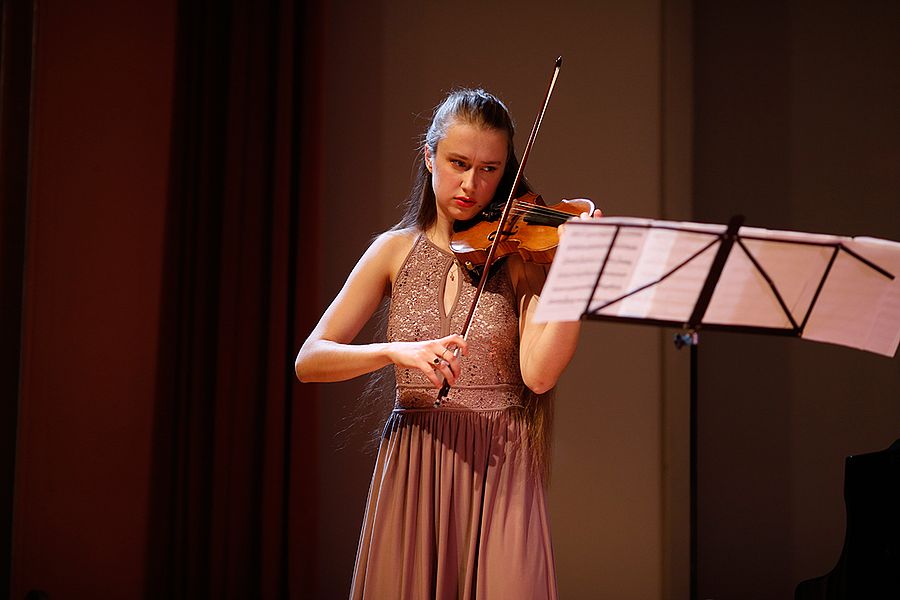 Studentin mit Geige und Noten auf einer Bühne