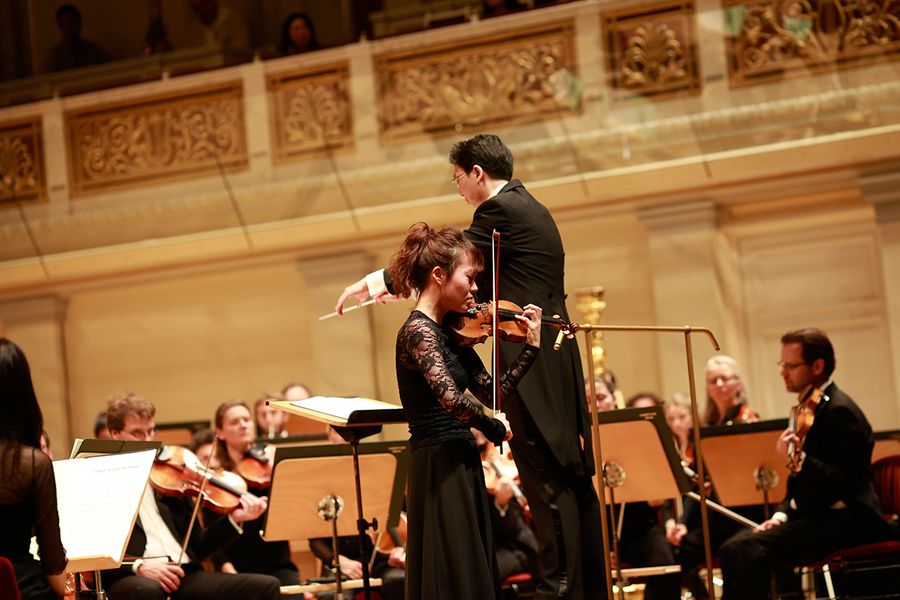 Geigensolistin und Dirigent vor dem Orchester auf der Bühne des Berliner Konzerthauses
