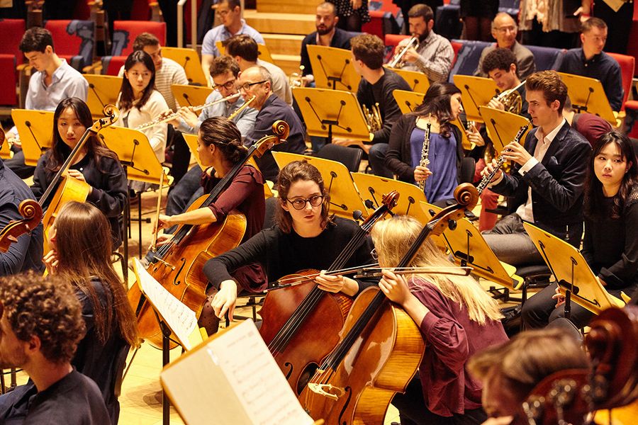Studierende und Lehrende mit Instrumenten während einer Orchesterprobe