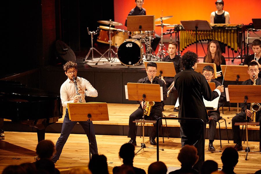 Klarinettensolist und Ensemble mit Dirigent auf einer Bühne während eines Konzertes