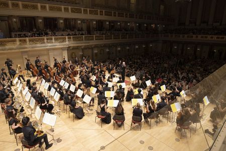 Ansicht auf das Orchester und Dirigent von hinter der Bühne