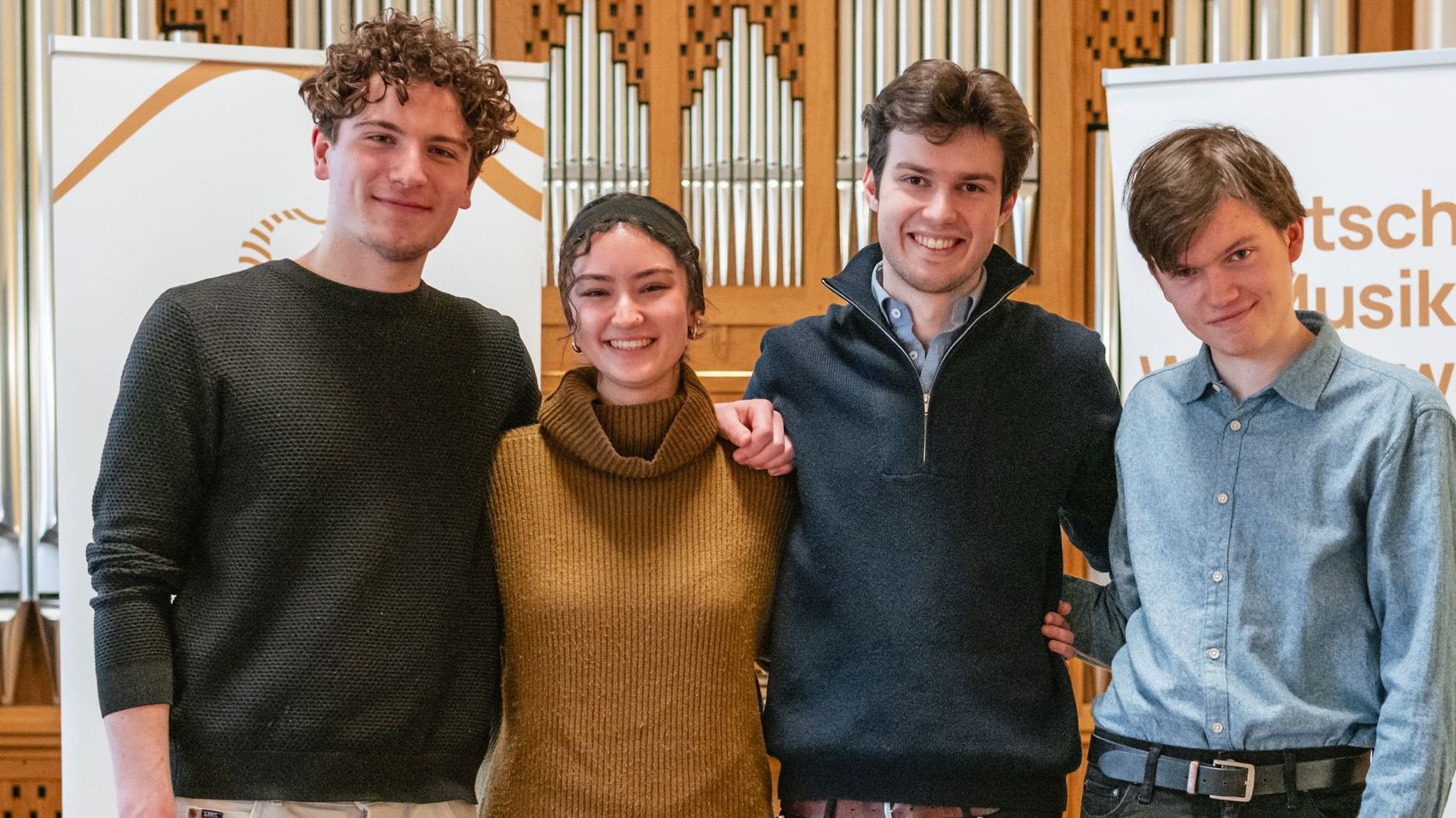 Vier junge Menschen vor dem Banner des Musikrats