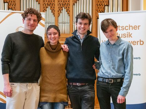 Vier junge Menschen vor dem Banner des Musikrats