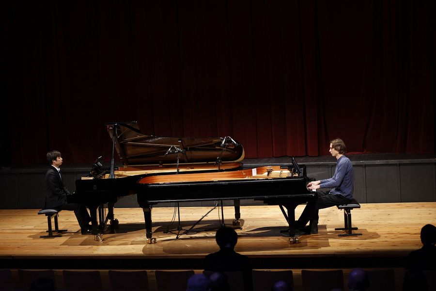 Zwei Studierende spielen auf der Bühne im Studiosaal Klavier