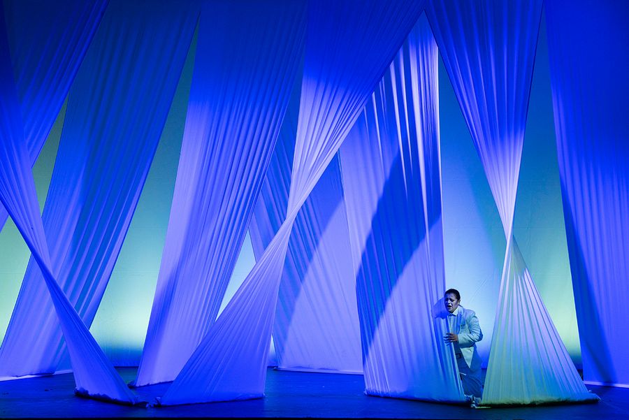 Gesangsstudentin auf einer blau beleuchteten Bühne mit weißen von der Decke hängenden Tuchbahnen