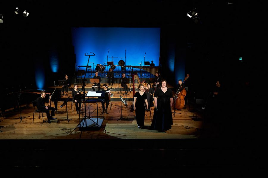 Studierenden-Ensemble und Gesangssolist*innen auf einer Bühne nach beendigtem Konzert