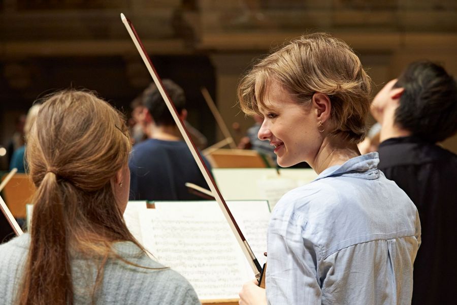 zwei Geigerinnen reden miteinander während Orchesterprobe