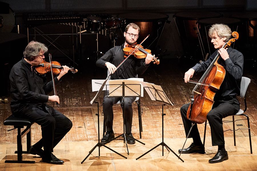 Zwei Professoren und Student mit Geige, Bratsche und Cello auf einer Bühne während eines Konzertes