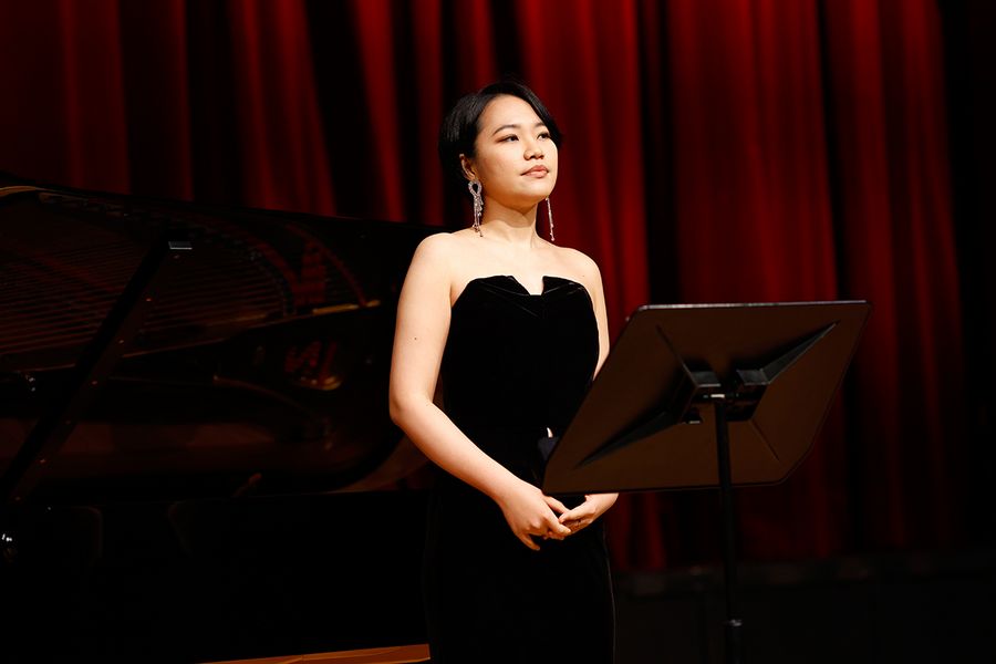  Gesangstudentin auf der Bühne des Studiosaals vor rotem Vorhang