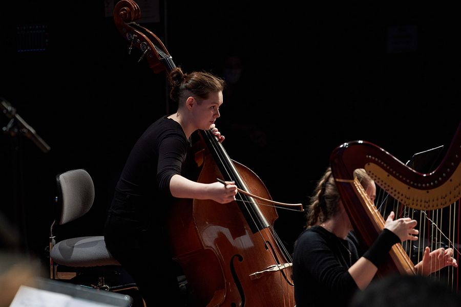 Zwei Studentinnen spielen Kontrabass und Harfe während einer Probe