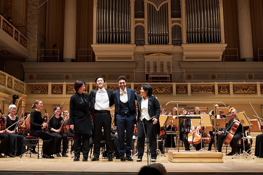Vier Dirigierstudierende stehen auf der Bühne des Berliner Konzerthauses vor einem Orchester