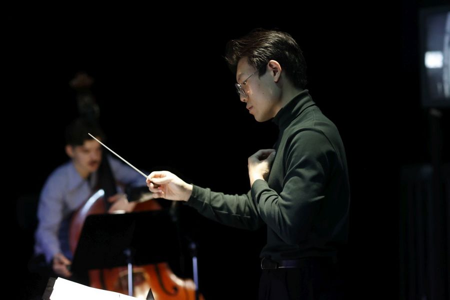 Ein Dirigent steht vor einem kleinen Orchester