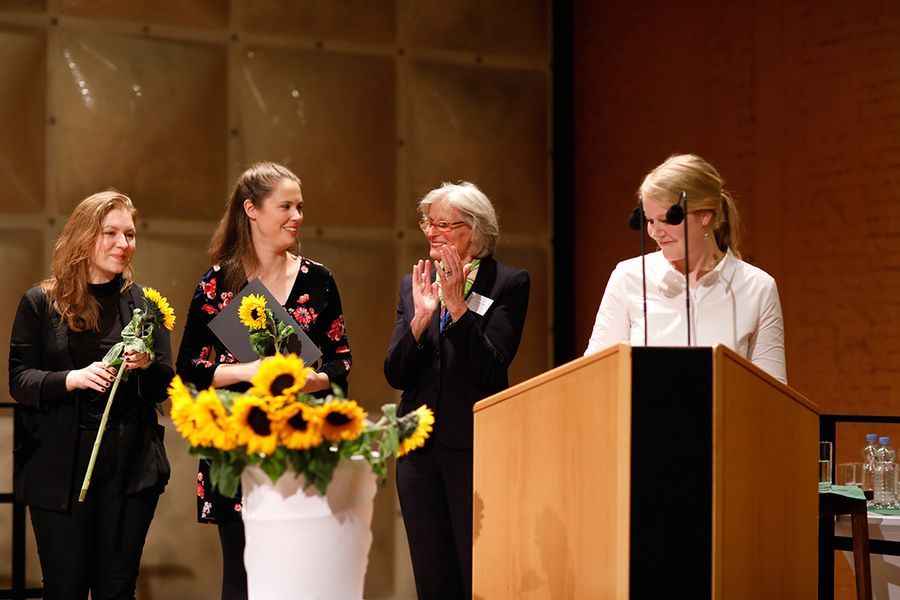 Zwei Stipendiatinnen, Fördervereinvorsitzende und Stipendienbeauftragte auf einer Bühne mit Sonnenblumen