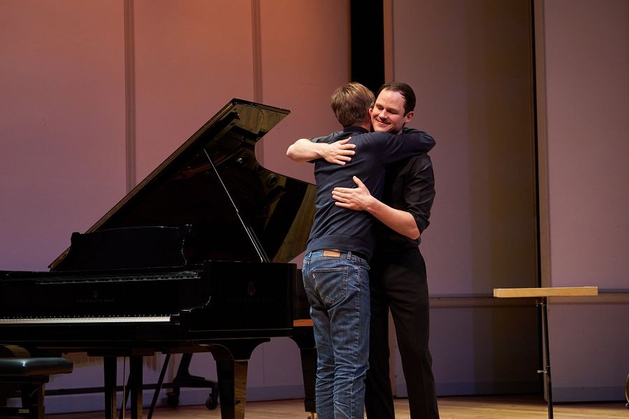 Ein Student steht auf der Bühne des Kleinen Saals im Berliner Konzerthaus und umarmt einen anderen Mann