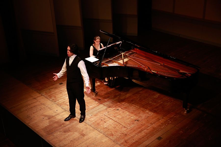 Singender Student und Frau am Flügel auf einer Bühne
