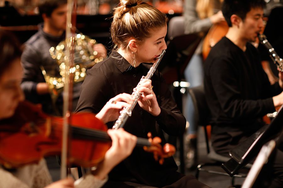 Studentin mit Flöte während einer Probe mit anderen Studierenden mit Instrumenten