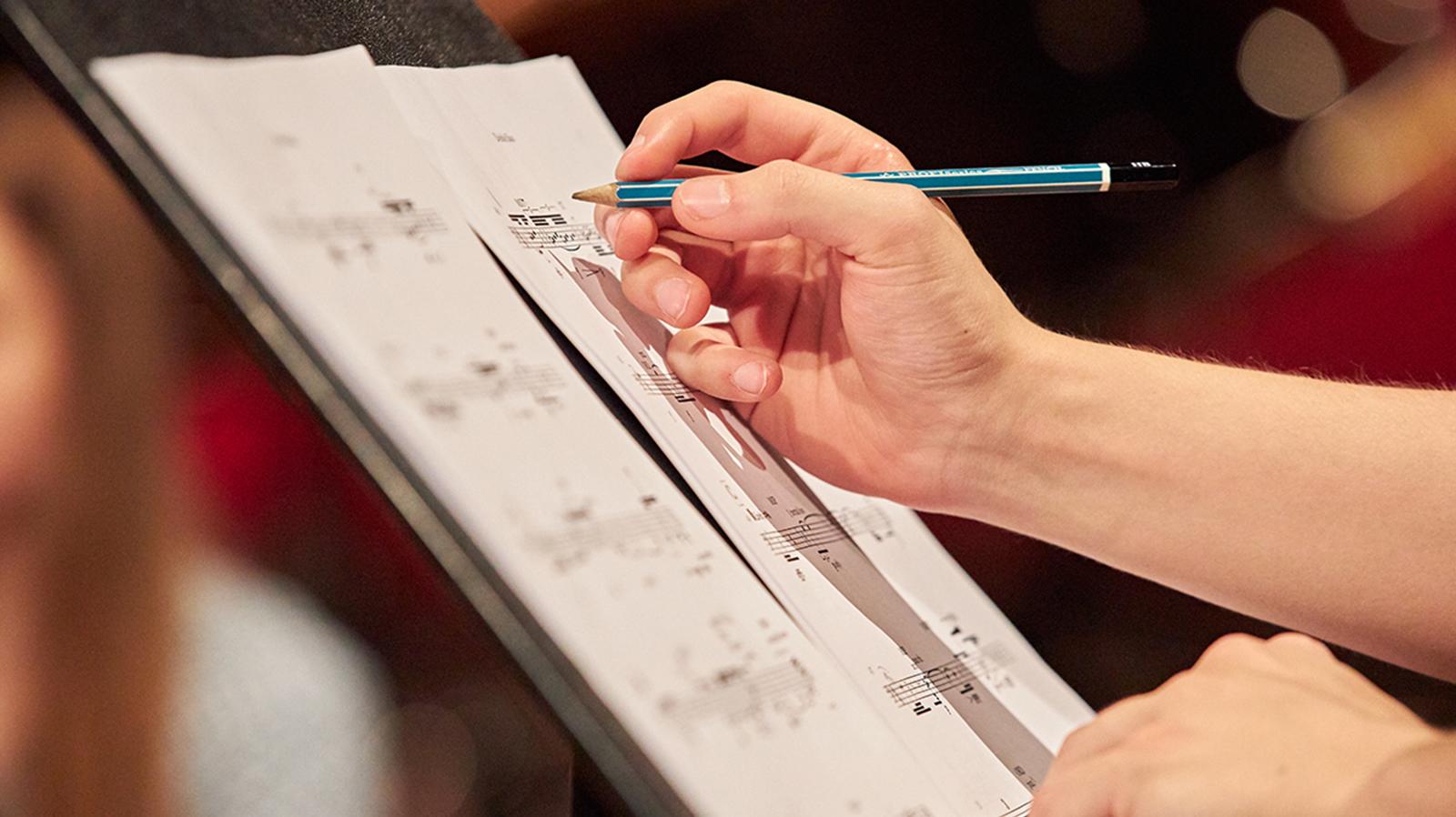 Studierende*r trägt sich Notizen in die Noten ein 