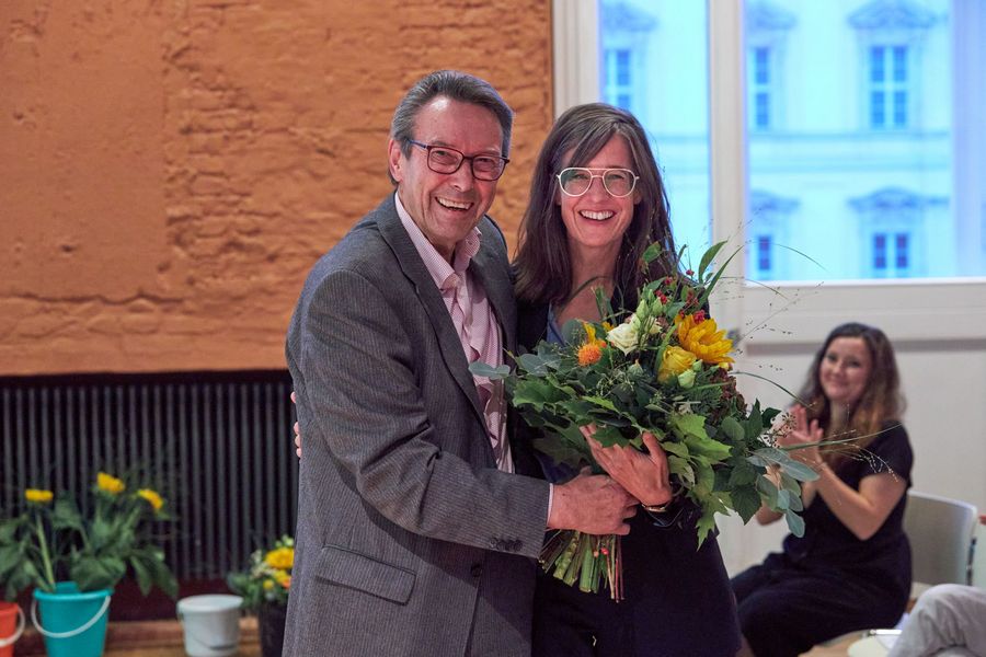 Mann und Frau stehen mit Blumenstrauß im Hintergrund wird applaudiert