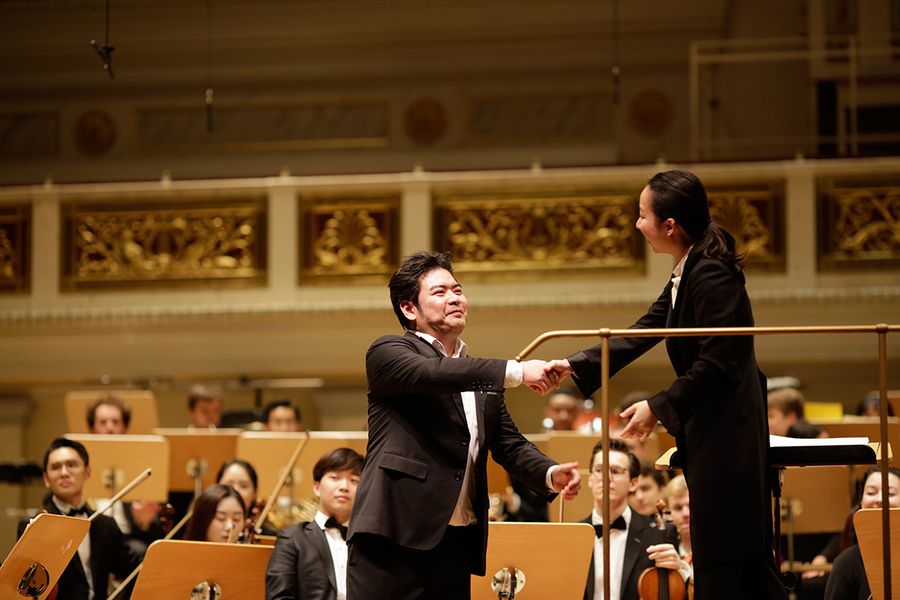 Sänger und Dirigentin reichen sich die Hand vor dem Orchester