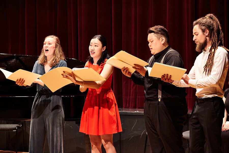 Singende Studierende auf einer Bühne mit Noten