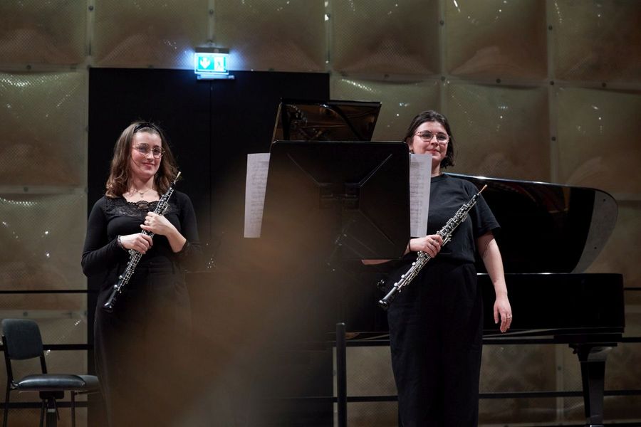 Zwei Studentinnen stehen auf der Bühne und halten Oboen in der Hand