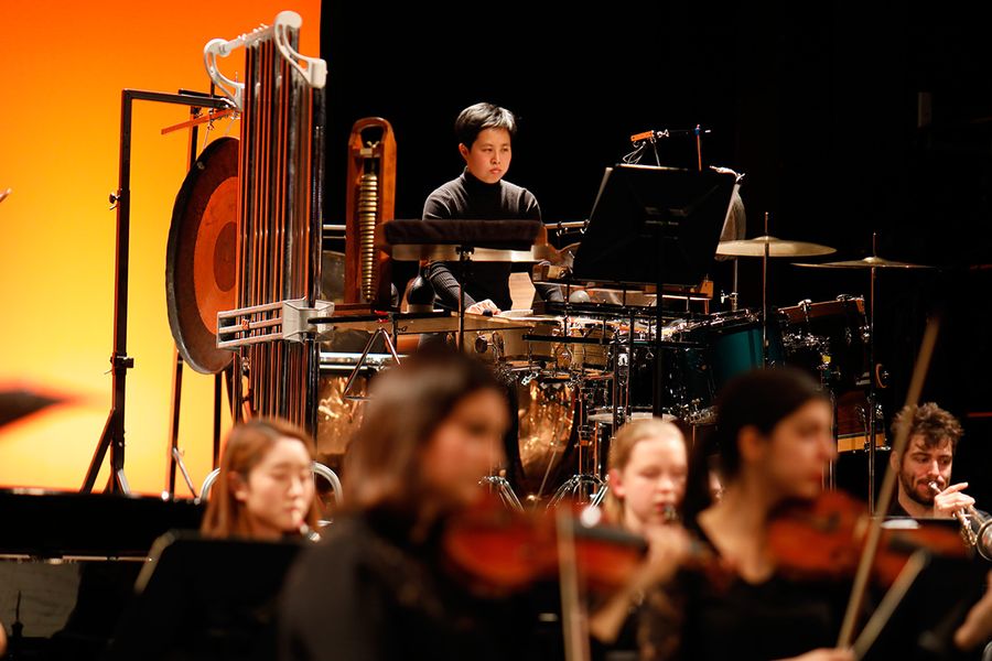 Studentin am Schlagwerk hinter einem Ensemble auf einer Bühne währende eines Konzertes