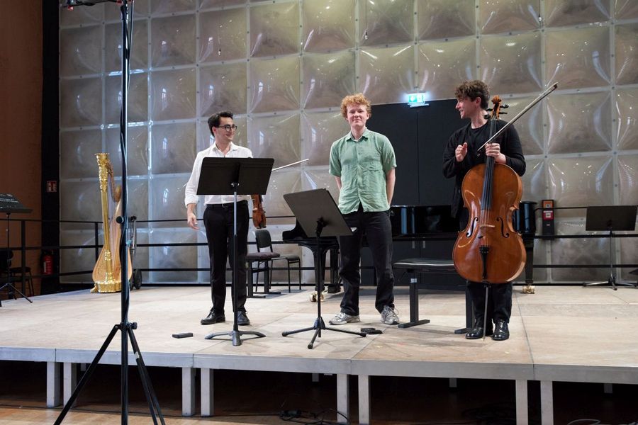 Geiger, Komponist und Cellist stehen auf der Bühne des Krönungskutschen-Saals