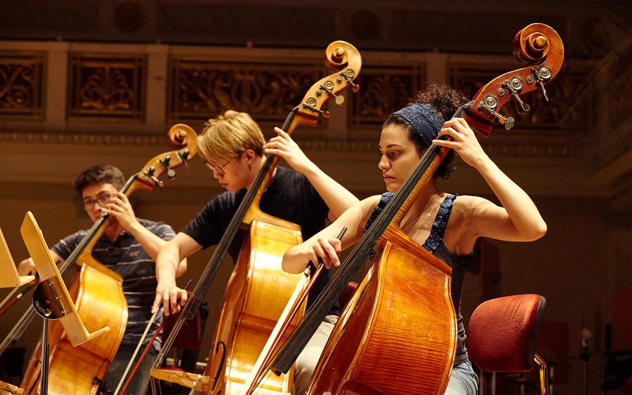 Drei Studierende mit Kontrabässen während einer Probe im Konzertsaal des Berliner Konzerthauses