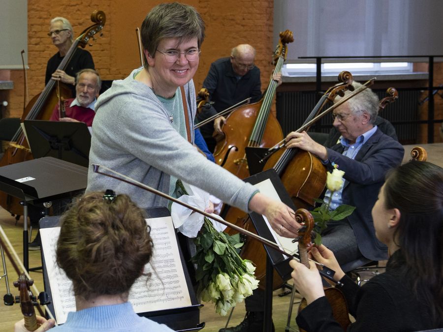 lächelnde Frau steht mit Blumen vor dem Orchester