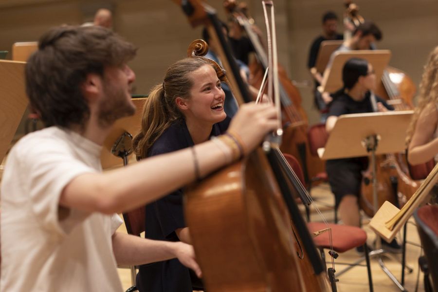 Student und Studentin mit Cello lachen 