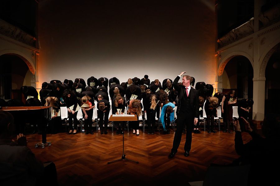 Dirigent zeigt auf einen sich verbeugende Chor aus Studierenden 