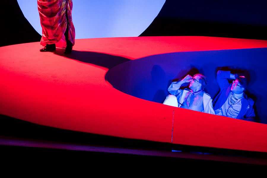 Drei Gesangstudierende während einer Musiktheater-Probe mit grell leuchtendem Bühnenbild