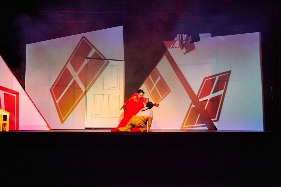 eine Sängerin sitzt auf der Bühne, über ihr steh eine Sängerin in einem roten Kleid